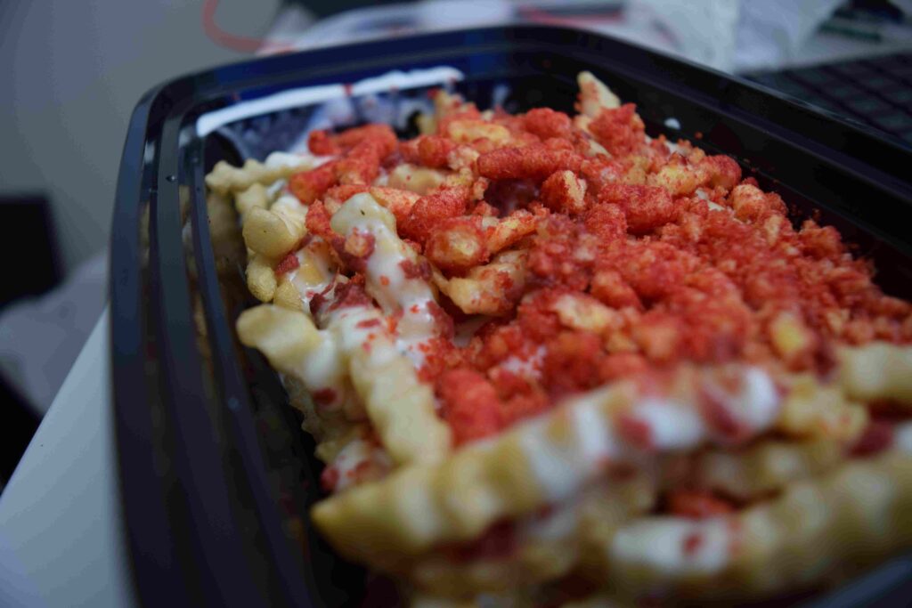 Close up photo of crinkle cut fries with ranch and crushed flamin hot cheetos on it